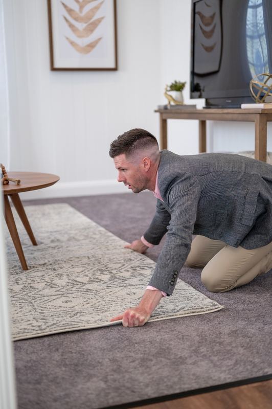 RealWay agent straightening a rug before an open home