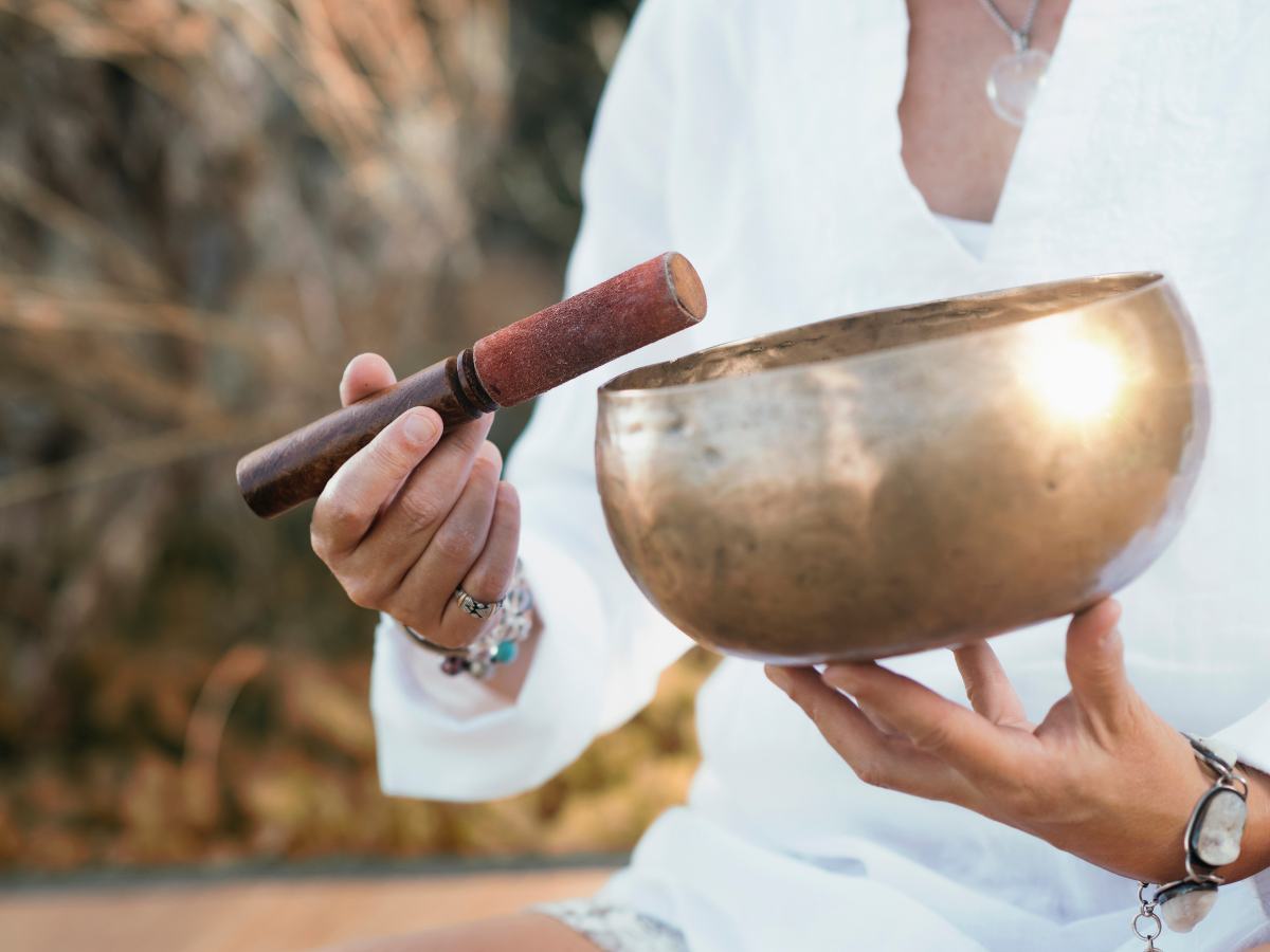Person holding a singing bowl and wooden mallet during a sound meditation session.