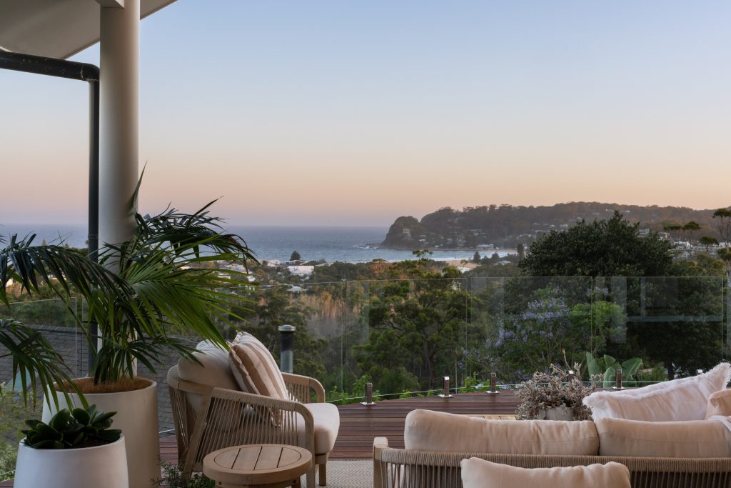 Covered deck with lounge seating looking over North Avoca to the ocean at dusk