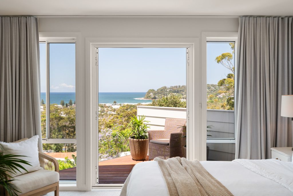 Bedroom opening onto a balcony with ocean and headland views at North Avoca