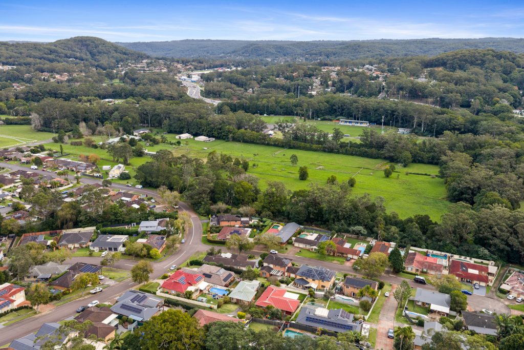Aerial view over Lisarow NSW showing homes, paddocks and the rail line