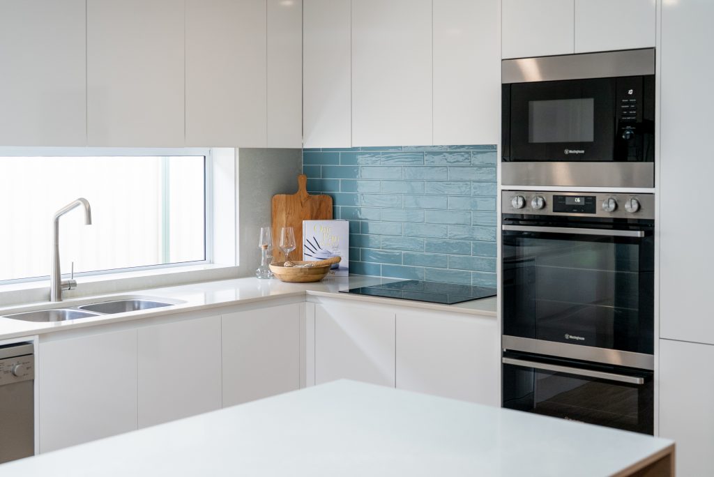 Modern white kitchen with blue tiled splashback in a Niagara Park home