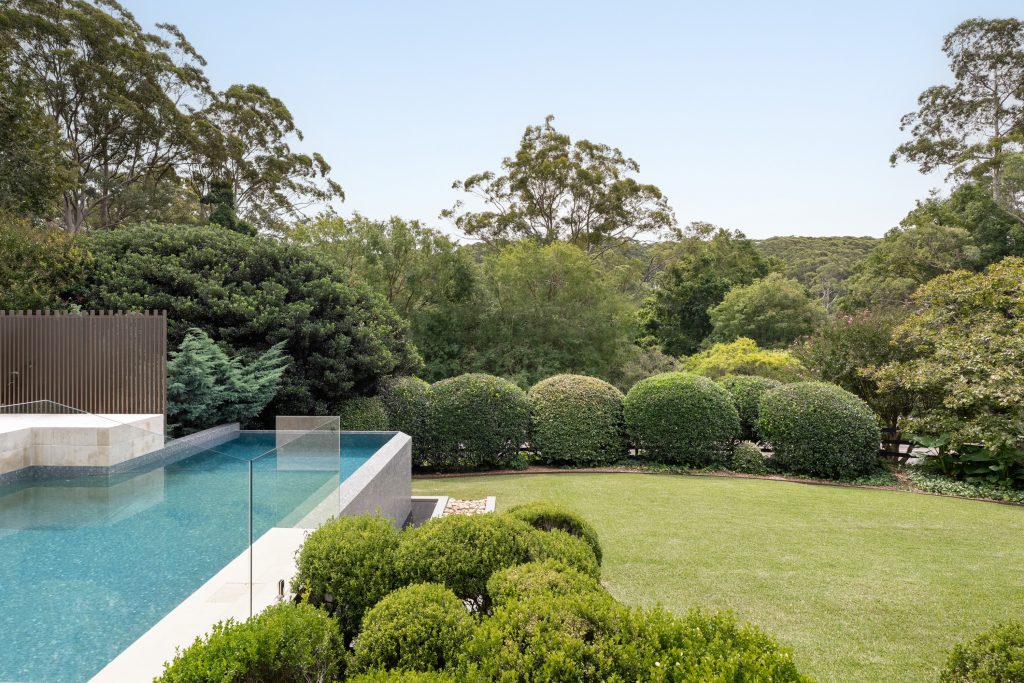 Infinity edge pool and manicured lawn backing onto bushland at a Matcham property