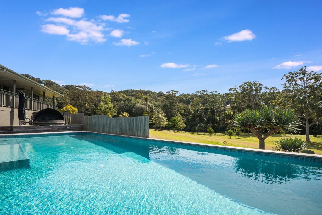 Swimming pool and covered terrace looking out to fenced paddocks at a Tumbi Umbi acreage property