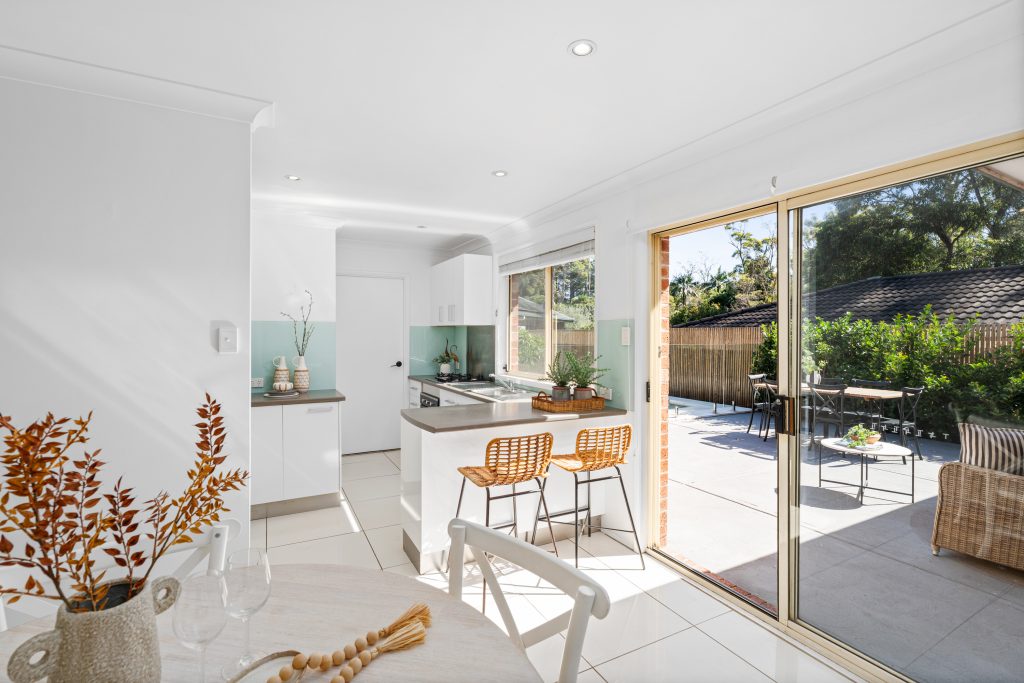Renovated open plan kitchen and dining area opening onto a paved courtyard at a Kariong home